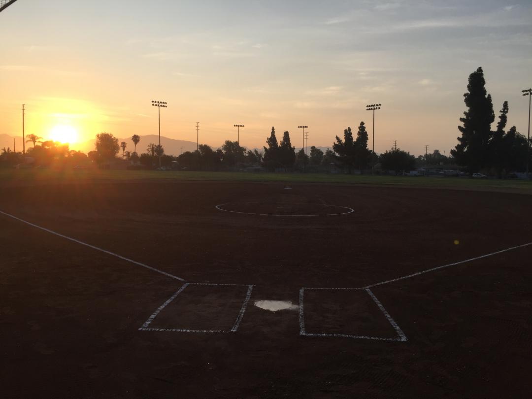 baseball field with the sun setting in the background